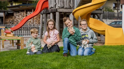 Kinder mit Hasen am hoteleigenen Spielplatz