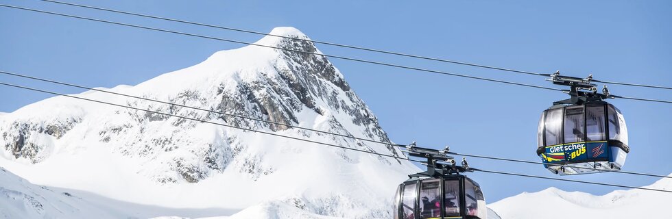 Gondeln vor verschneitem Berggipfel